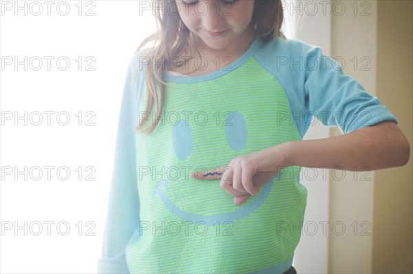 Caucasian girl holding mustache over smiley face shirt