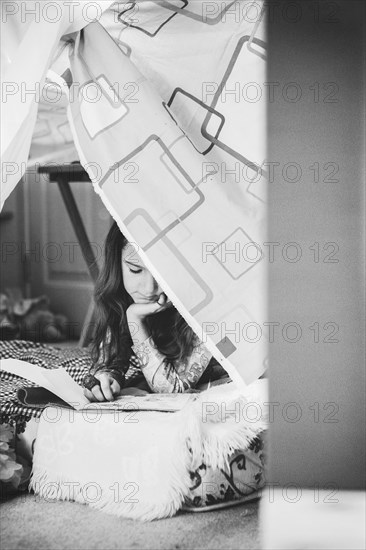 Caucasian girl reading in pillow fort