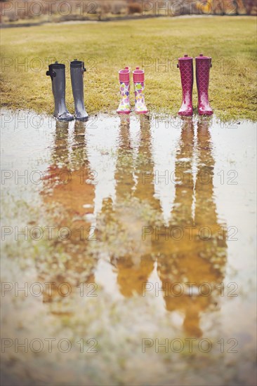 Reflection of people from rain boots in puddle