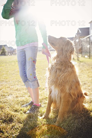 Caucasian girl walking dog in field