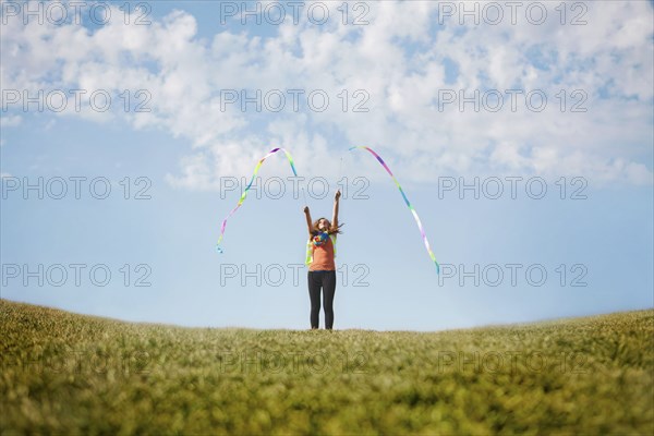 Caucasian girl playing with ribbons on hilltop