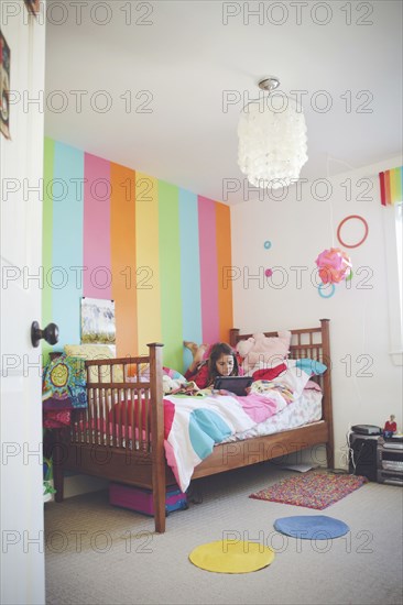 Caucasian girl using digital tablet in bedroom