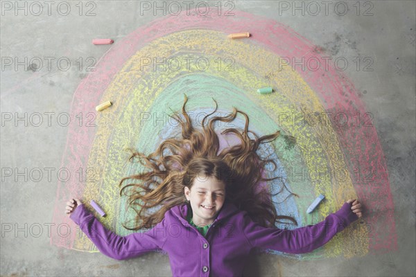 Caucasian girl laying on chalk rainbow