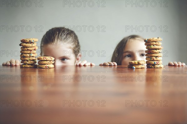 Caucasian girls staring at cookies on table