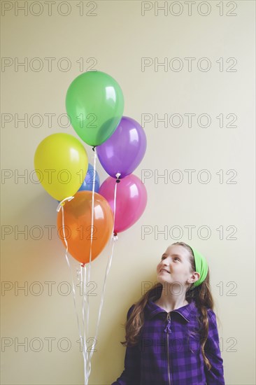 Caucasian girl holding bunch of balloons