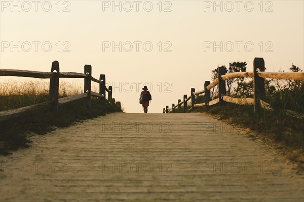 Silhouette of woman walking on wooden walkway