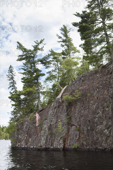 Caucasian girl jumping into lake from cliff