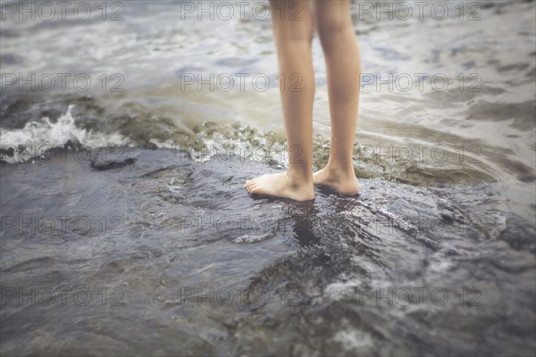 Caucasian girl standing in ocean waves