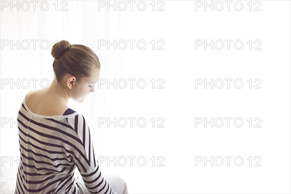 Caucasian girl sitting at sheer curtains