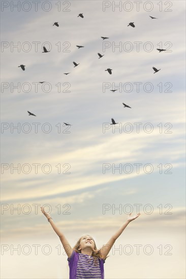 Caucasian girl cheering under flock of birds