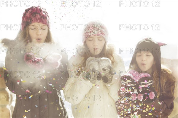 Caucasian girls blowing snow off mittens