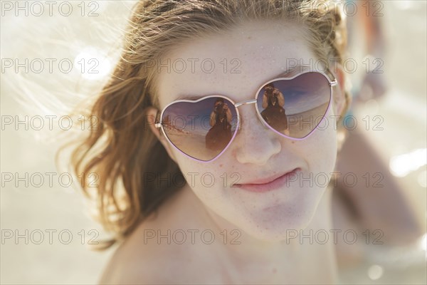 Caucasian teenage girl wearing heart-shaped sunglasses