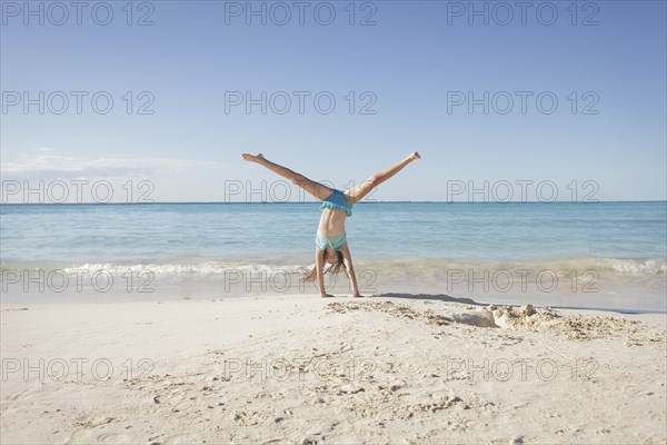 Caucasian girl doing cartwheel on beach