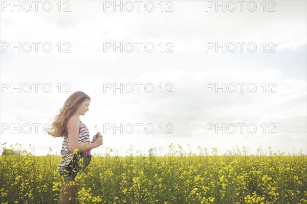 Caucasian teenage girl standing in field of flowers