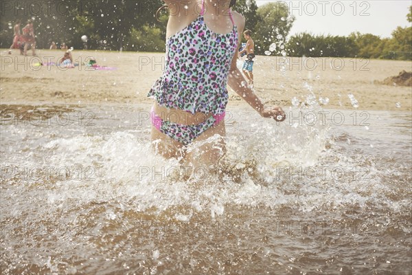 Caucasian girl splashing in waves on beach