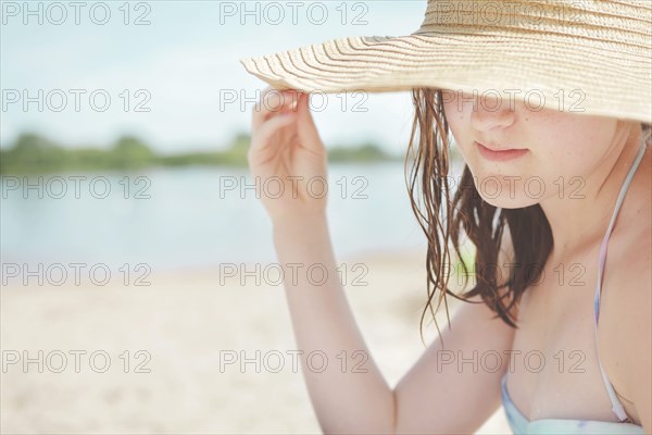 Caucasian teenage girl wearing sun hat on beach