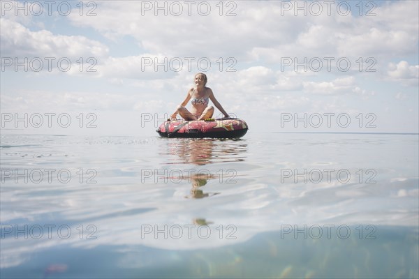 Caucasian teenage girl floating in inner tube on lake