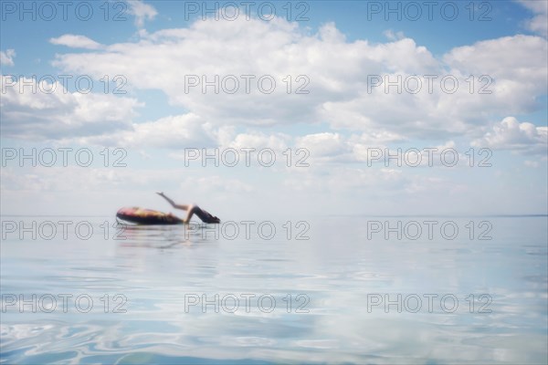 Caucasian teenage girl jumping from inner tube into lake