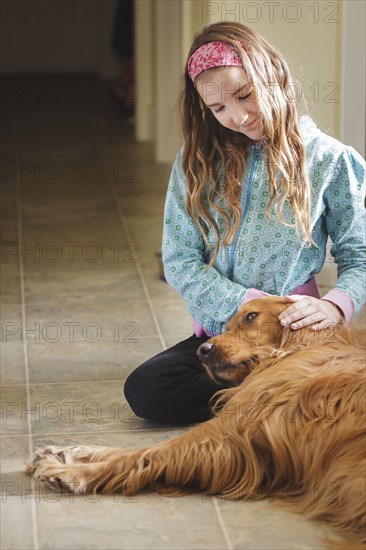 Caucasian girl petting dog on floor