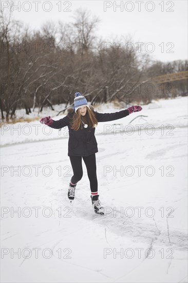 Caucasian teenage girl ice skating on frozen lake