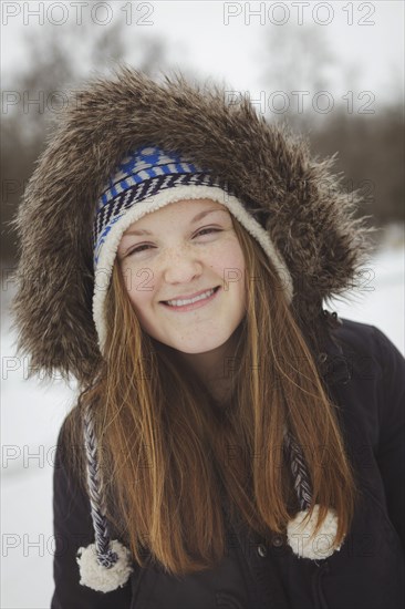 Caucasian teenage girl wearing fur coat and hat in snow