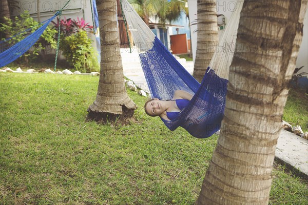 Caucasian girl laying in hammock in backyard