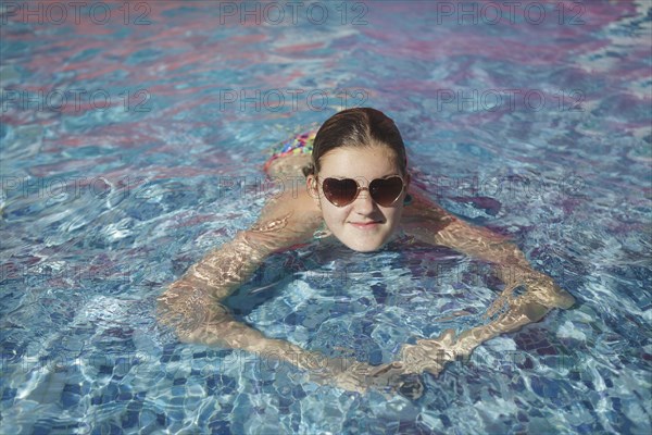 Caucasian teenage girl wearing sunglasses in swimming pool