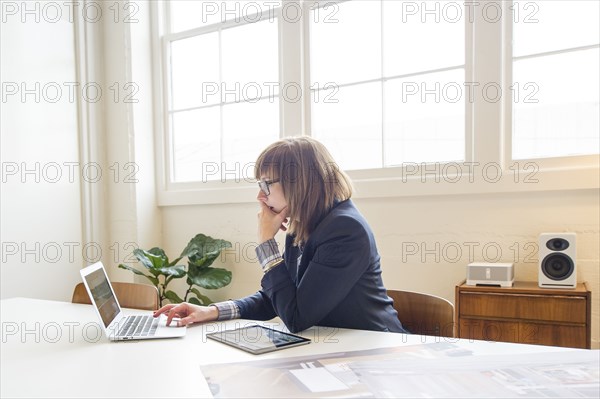 Businesswoman using laptop at desk in office