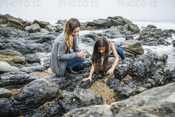 Hispanic mother and daughter exploring tide pools