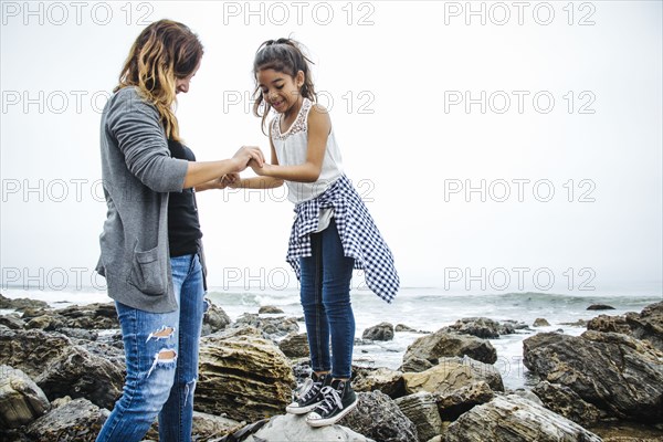 Hispanic mother and daughter exploring tide pools