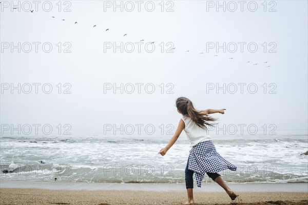 Hispanic girl playing on beach