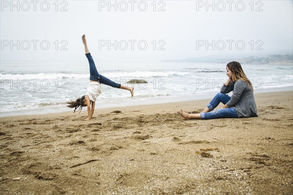 Hispanic mother and daughter playing on beach