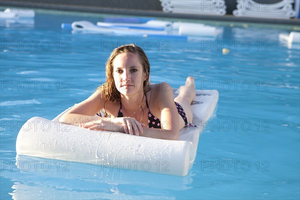 Woman floating on raft in swimming pool