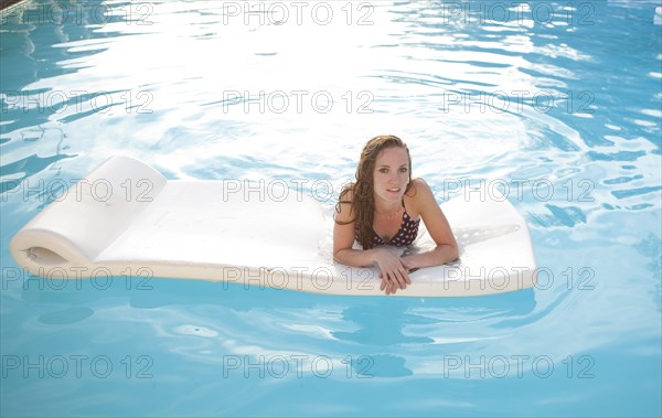 Woman floating on raft in swimming pool