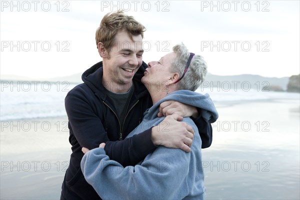 Caucasian mother and son hugging on beach