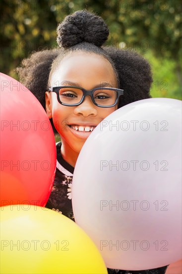 Black girl holding bunch of balloons