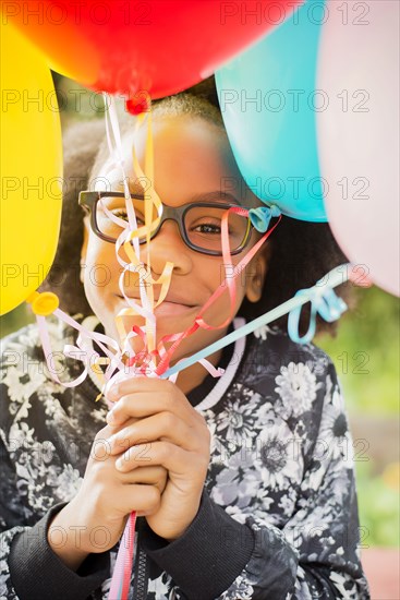 Black girl holding bunch of balloons