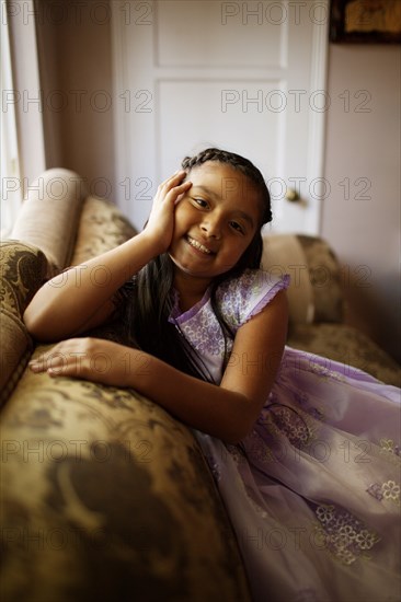 Hispanic girl sitting on sofa in living room