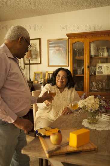 Couple toasting each other with wine in kitchen