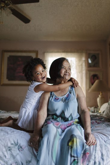 Grandmother and granddaughter hugging on bed