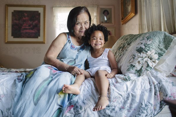 Grandmother and granddaughter hugging on bed