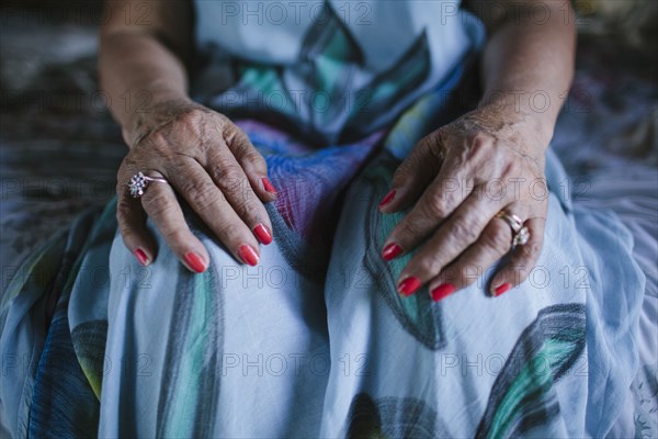 Close up of hands of older woman resting on knees