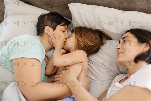 Caucasian mother kissing daughter in bed