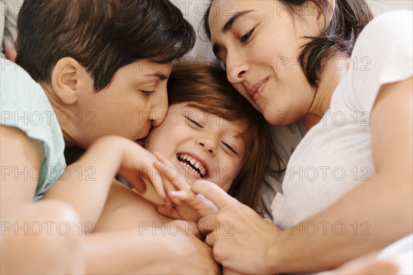 Caucasian family cuddling in bed