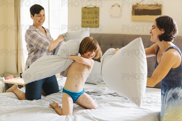 Caucasian family having pillow fight in bedroom