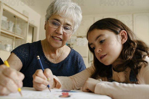 Grandmother and granddaughter drawing at table