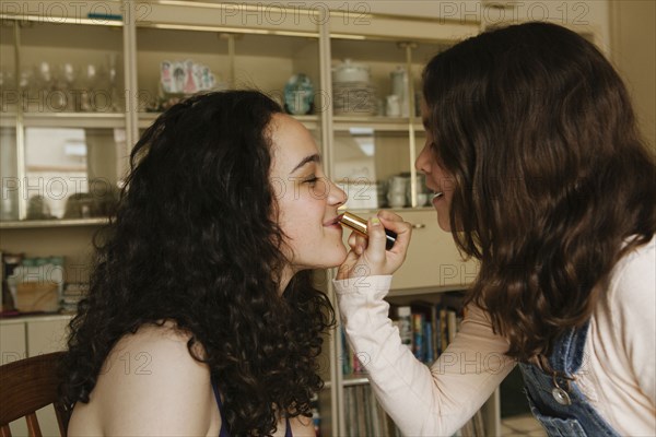 Girl applying lipstick on sister
