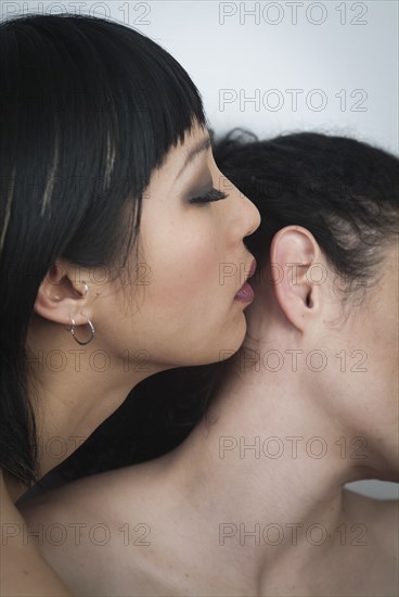 Woman whispering secret into ear of another woman