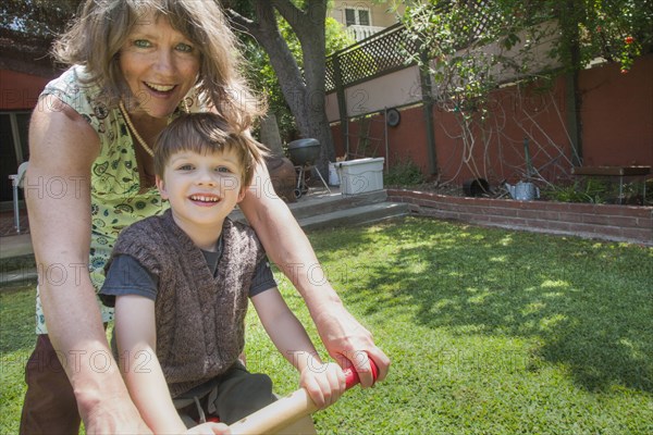 Caucasian grandmother and grandson riding bicycle in backyard