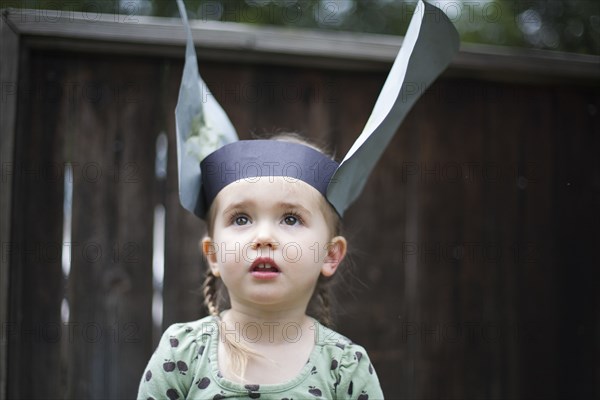 Caucasian girl wearing paper hat in backyard